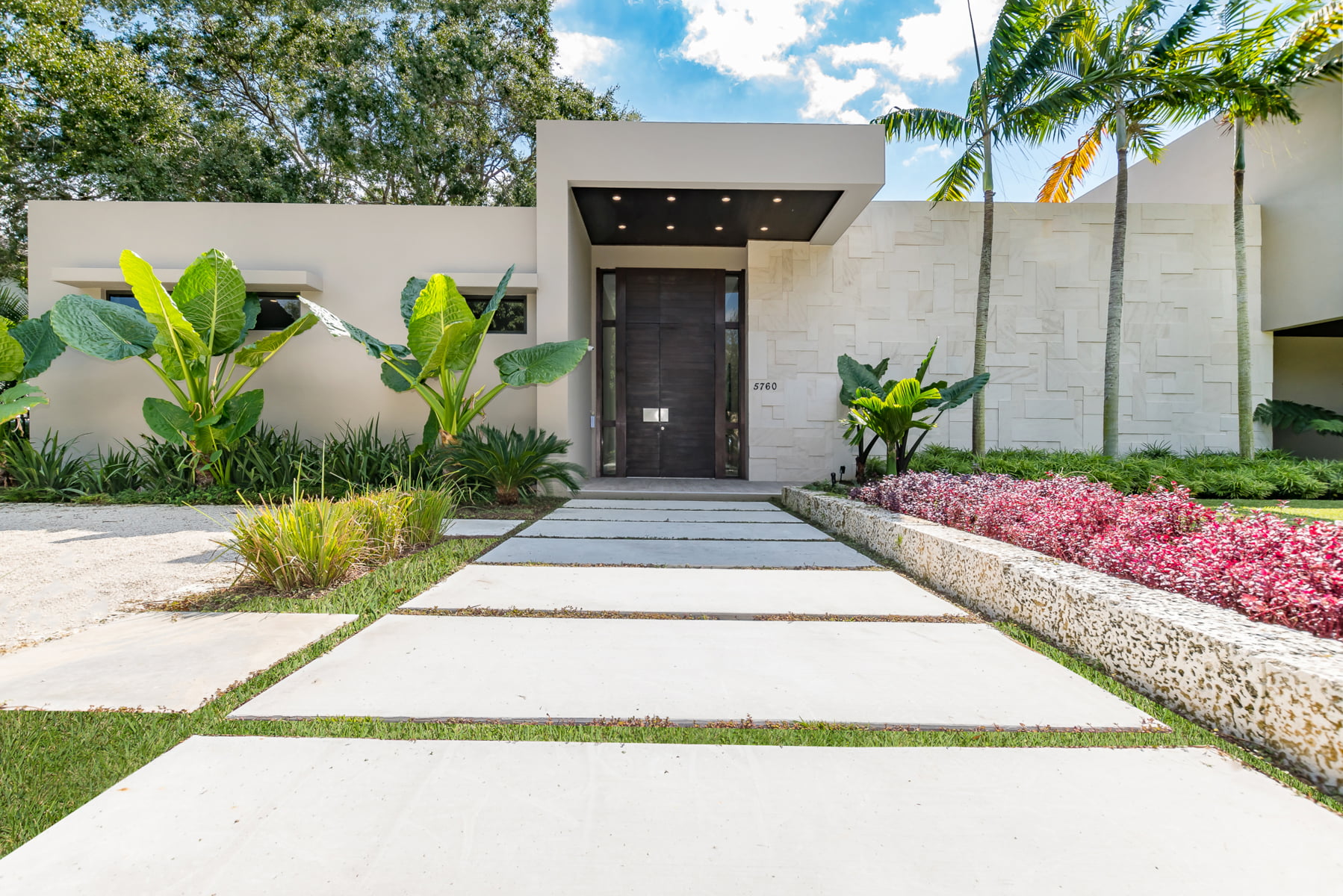 A sleek white home with colorful greenery suggesting an answer to who builds contemporary homes in miami