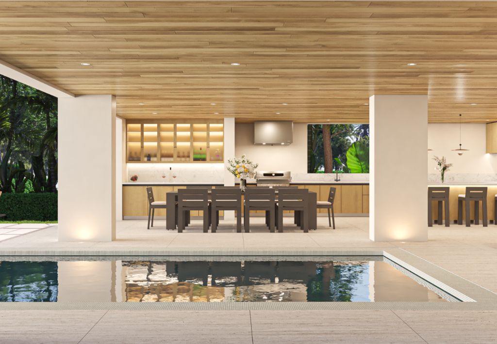 Modern open-air kitchen and dining area with wooden ceiling, recessed lighting, and a large table set for eight, offering resort style living and overlooking a pool framed by lush greenery outside.