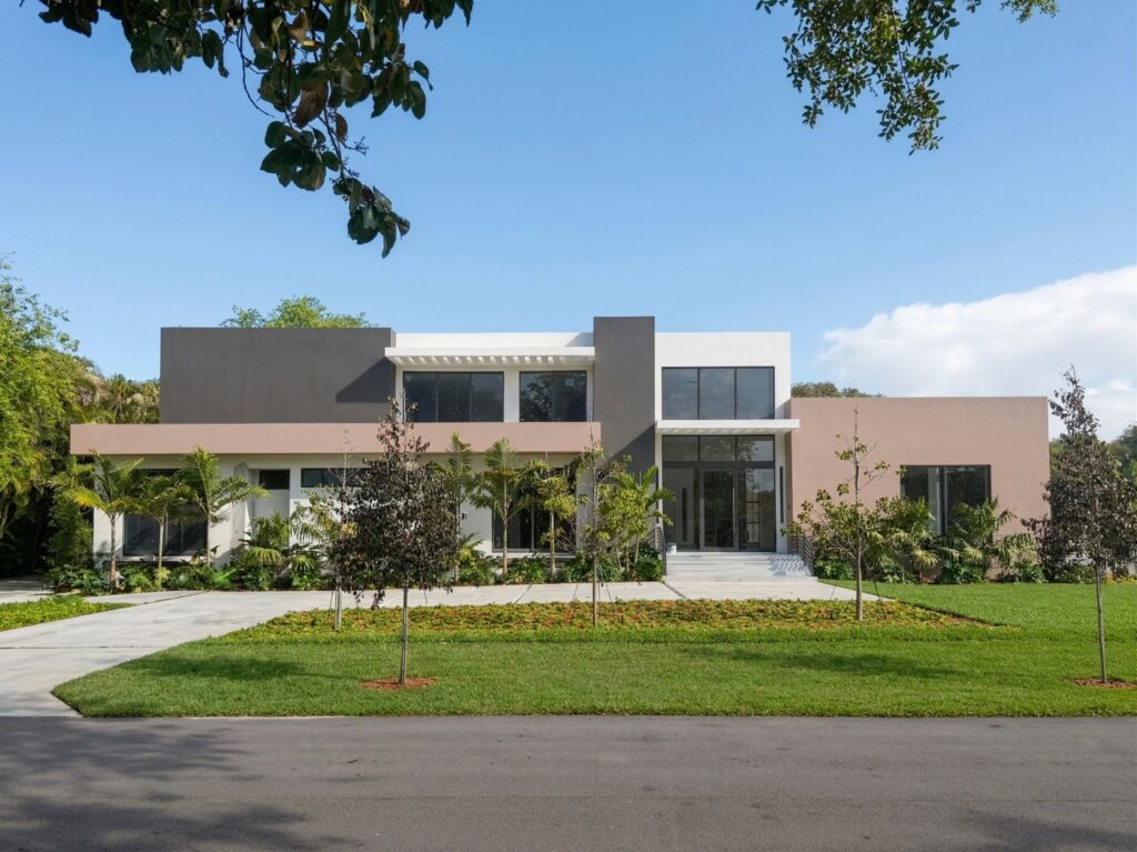A modern two-story house, built as a ground up new construction, features clean lines, large windows, and a flat roof, surrounded by a manicured lawn, small trees, and palm trees under a blue sky.
