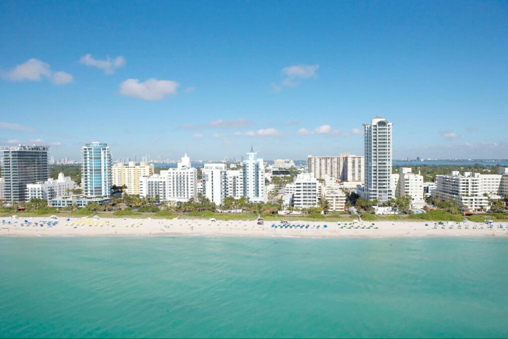 Aerial view of a sandy beach lined with high-rise hotels and apartments along the oceanfront. Tranquil scenery and urban living is what life in miami is all about.